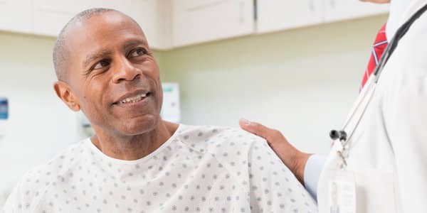 Doctor speaking with a patient wearing a hospital gown during a medical visit