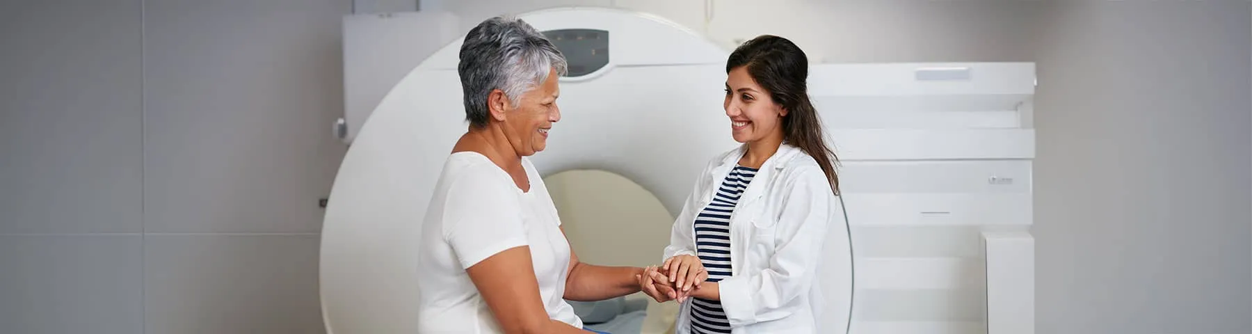 Patient and healthcare professional talking beside a medical imaging scanner
